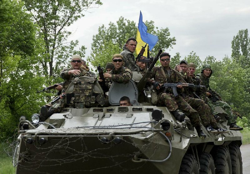 Ukrainian soldiers sit on top of an APC leaving the site of a Ukrainian check point that came under attack by pro-Russians near the village of Blahodatne, eastern Ukraine, on Thursday, May 22, 2014. Several Ukrainian troops were killed and many others were wounded when Pro-Russians attacked a military checkpoint, the deadliest raid in the weeks of fighting in eastern Ukraine. (AP Photo/Vadim Ghirda)