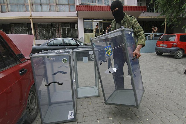 A pro-Russia activist prepares to smash a ballot box Friday near a polling station in Donetsk, Ukraine. Ukraine’s government has admitted that it will not be able to organize the voting in parts of eastern Ukraine, which is overrun with pro-Russia insurgents. 