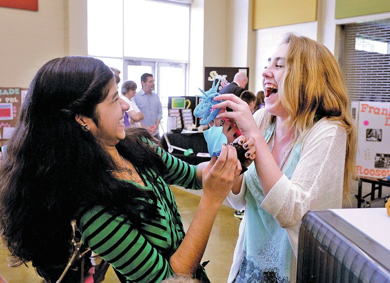 STAFF PHOTO BEN GOFF Mirudula Manivannan, 13, left, and Hannah Wilkin, 14, both Fulbright students, horse around with plastic figures on display with a 3D printer from Washington Junior High School.