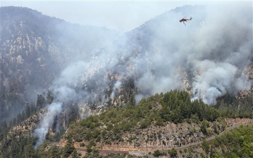 A Heavy Type-1 Skycrane Helictoper flies over the Slide Fire, above the route 89 A, before dumping a 2,000 gallon load of water as it burns up Oak Creek Canyon on Friday, May 23, 2014, near Flagstaff, Ariz. The fire has burned approximately 7,500 acres and is five percent contained.