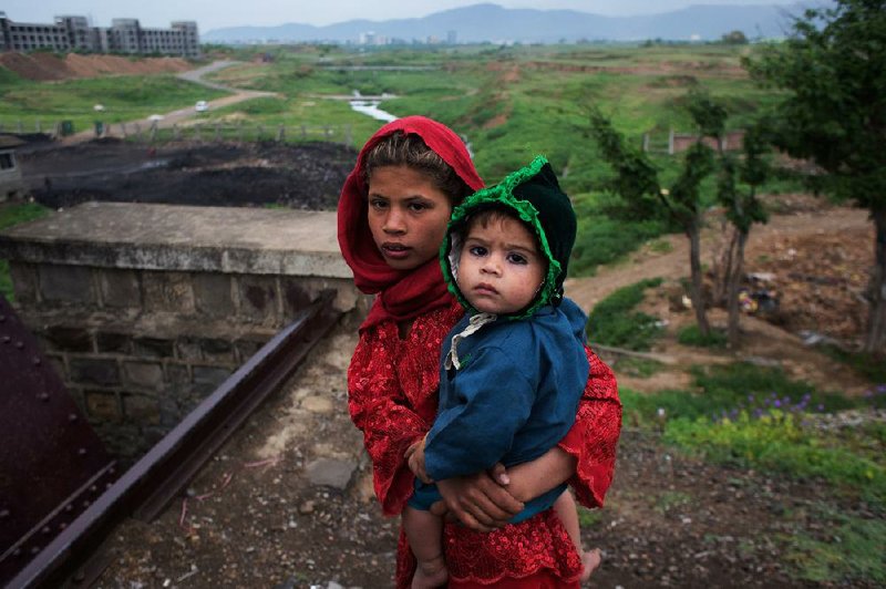 An Afghan girl carries her brother through the ruins of their refugee community in Islamabad after Pakistani authorities sent bulldozers to raze the settlement. 