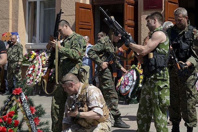 Pro-Russian militants check their weapons during a funeral, attended by thousands, for five pro-Russian activists, Saturday, May 24, 2014, in the town of Stakhanov, eastern Ukraine. Five insurgents killed in a battle with Ukrainian forces near the city of Luhansk were buried on Saturday. The clash is one of several firefights between the two sides that have left at least 20 dead and some 300 injured, according to the Ukrainian Defense Ministry, days ahead of the country's presidential elections. (AP Photo/Vadim Ghirda)