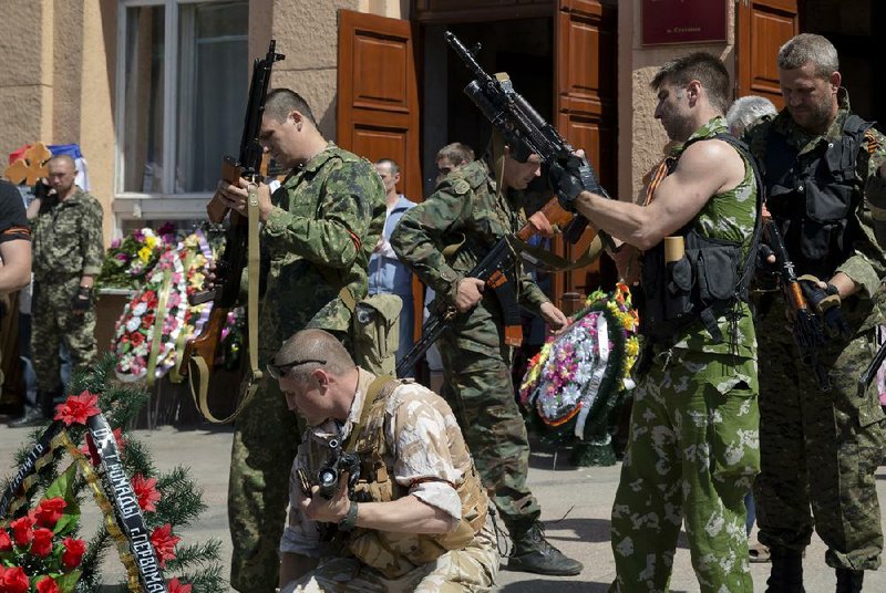 Pro-Russian militants check their weapons during a funeral, attended by thousands, for five pro-Russian activists, Saturday, May 24, 2014, in the town of Stakhanov, eastern Ukraine. Five insurgents killed in a battle with Ukrainian forces near the city of Luhansk were buried on Saturday. The clash is one of several firefights between the two sides that have left at least 20 dead and some 300 injured, according to the Ukrainian Defense Ministry, days ahead of the country's presidential elections. (AP Photo/Vadim Ghirda)