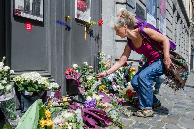 A woman lays flowers at the Jewish Museum in Brussels, Sunday May 25, 2014.  Police stepped up security at Jewish institutions, schools and synagogues after three people were killed and one seriously injured in a spree of gunfire at the Jewish Museum in Brussels on Saturday. (AP Photo/Geert Vanden Wijngaert)