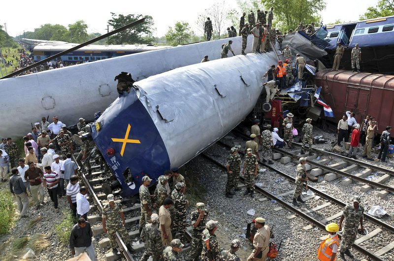 Indian officials and rescuers stand near the wreckage after the Gorakhpur Express passenger train slammed into a parked freight train Chureb, near Basti, Uttar Pradesh state,, India, Monday, May 26, 2014. According to officials dozens were killed. 