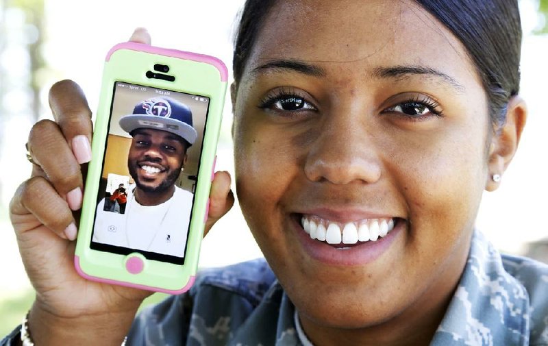 Kashmere Farmer shows how FaceTime lets her see her husband, Atarius, during phone conversation. The newlyweds stay in touch during their distant deployments by texting and video-chatting with their mobile devices and computers. 