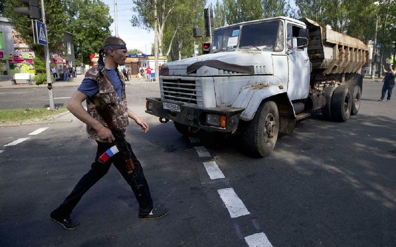 A pro-Russia militia member works a to the airport in Donetsk, Ukraine, on on a road leading . 