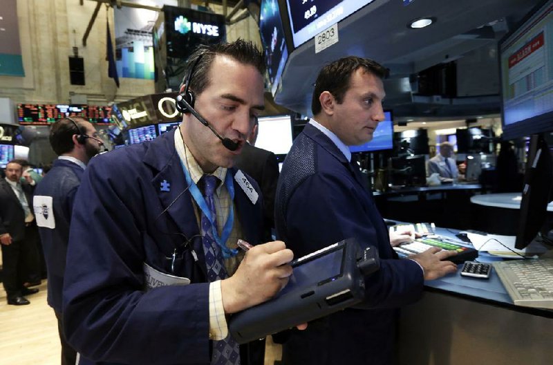 Trader Gregory Rowe (front) works Tuesday on the floor of the New York Stock Exchange. Stocks closed higher as investors reacted to reports about consumer confidence and sales of durable goods. 