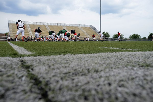 Bentonville players run through situational game plays Friday, May 23, 2014, during Bentonville High School's spring practice at Tiger Stadium in Bentonville. The team will be getting a new turf field over the summer.