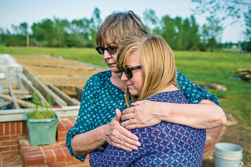 Karla Stracener hugs her daughter, Tillie, in front of the remnants of their family home in Center Hill. The home was destroyed by the area’s April 27 tornado.
