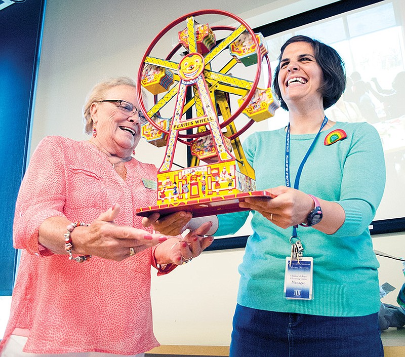 Beth Goeden, left, with the Hot Springs Vapor Valley Questers, presents an antique Ferris wheel toy to Sarah McClure, manager of the Hillary Rodham Clinton Children's Library and Learning Center. The toy is part of a program to donate special items to the library system for display.