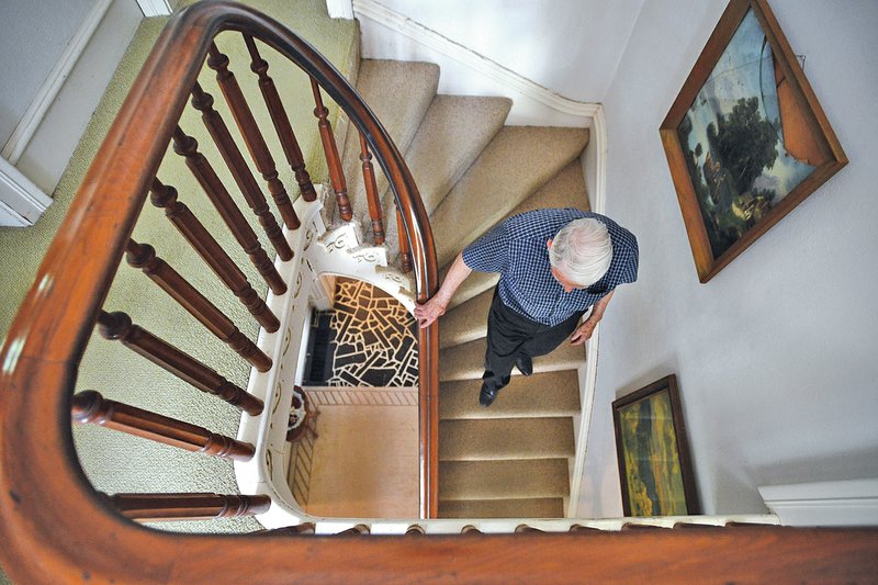 STAFF PHOTO BY SAMANTHA BAKER &#8226; @NWASamantha Sam Morrison walks down the staircase in his historical home May 23 at Northwest Second Street and North Walton Boulevard in Bentonville. The home was built in 1881 and Morrison has been living in it since 1968.