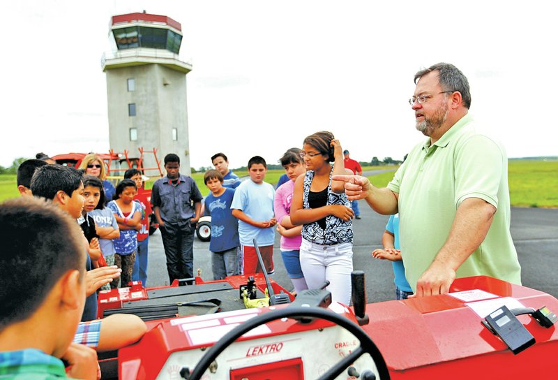 STAFF PHOTO JASON IVESTER Stephen Ricker explains the workings of an airplane tug to the fifth-graders at the airport.