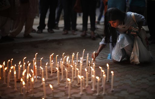 An activist places a candle on a pavement during a candle lit vigil to protest against the gang rape of two teenage girls, in New Delhi, India, Saturday, May 31, 2014. Police arrested a third suspect and hunted for two others Saturday in the gang rape and slaying of two teenage cousins found hanging from a tree in Katra village, in the northern Indian state of Uttar Pradesh, a case that has prompted national outrage.