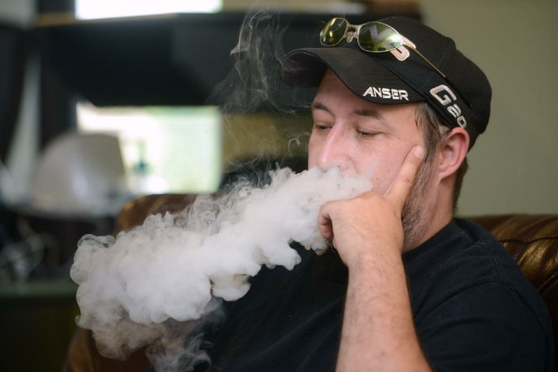 Matt Aten exhales while using an electronic cigarette last month. Aten had just purchased more flavoring for the device at Via Vapor Electronic Cigarette Emporium in Bentonville. 