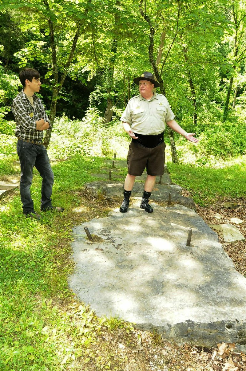 Intern Sebastian Rodriguez (left) and interpretive naturalist Steve Chyrchel stand Saturday near the foundation of a large steam-powered sawmill, part of a walk along the Historic Van Winkle Trail at Hobbs State Park-Conservation Area near Rogers. Lumber milled at the site was used to make many of the historic buildings in Northwest Arkansas, Chyrchel said. 