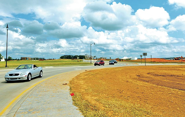 STAFF PHOTO JASON IVESTER Motorists make their way around the roundabout on Pauline Whitaker Parkway on Saturday in Rogers. Com-Scape is scheduled to be planting trees, shrubs and rose bushes today. A 16-foot tall southern magnolia tree will be planted as a centerpiece in the roundabout.