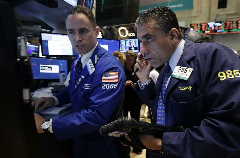 Specialist Jason Hardzewicz (left) and trader Vincent Quinones work Monday on the floor of the New York Stock Exchange. Stocks closed slightly higher Monday.