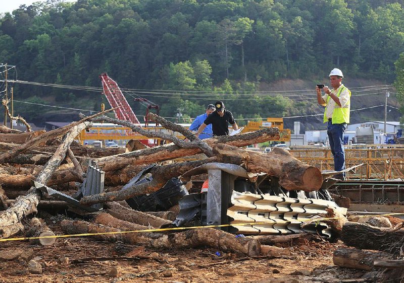Investigators examine a fatal accident scene in Clinton, where officials say a log truck lost control and flipped Monday, sending logs flying into construction workers on a bridge at U.S. 65 and Arkansas 16. 