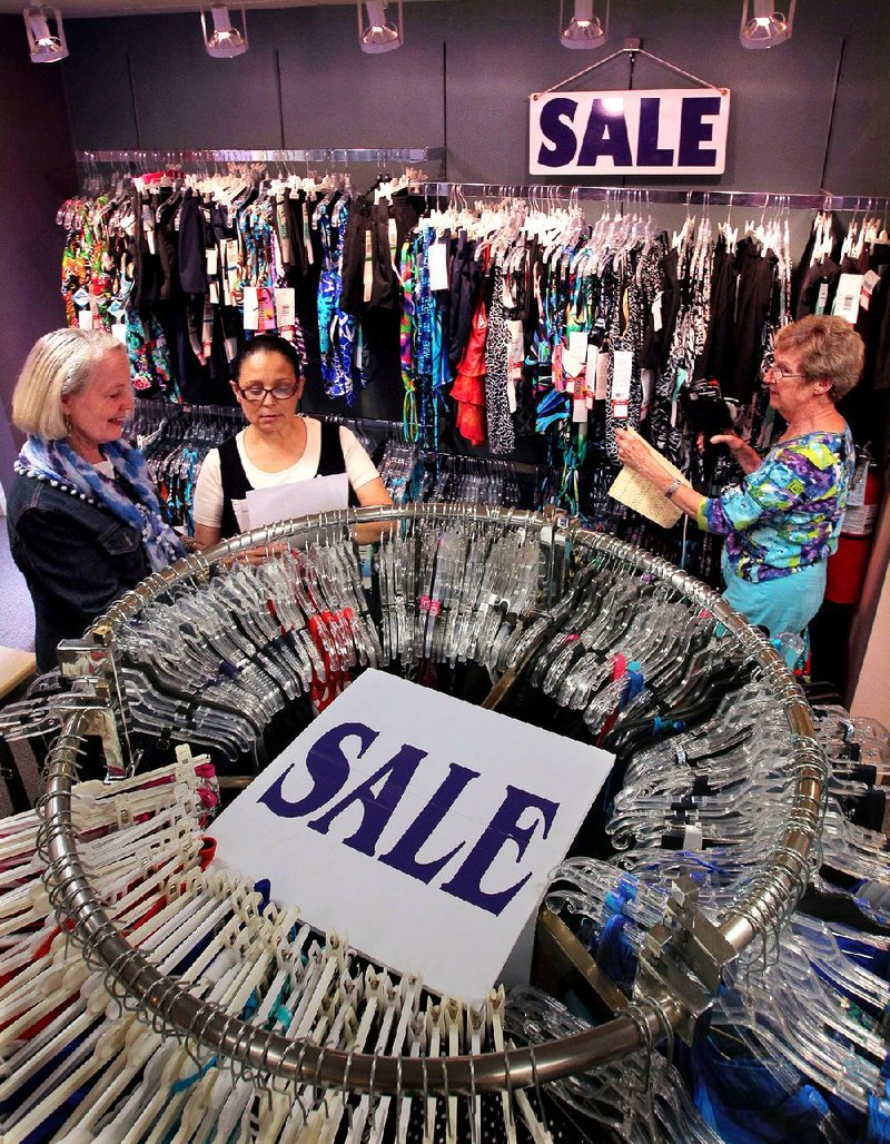 Barbara Graves (left) and employees Elsa Lawrence and Julie Clements mark down prices on merchandise for Graves’ retirement and liquidation sale, which starts today.