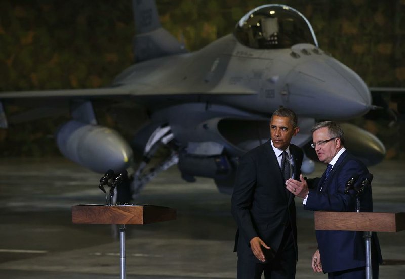 With an F-16 fighter for a backdrop in a hangar at Warsaw, President Barack Obama and Polish President Bronislaw Komorowski meet with a joint force of U.S. and Polish troops. 