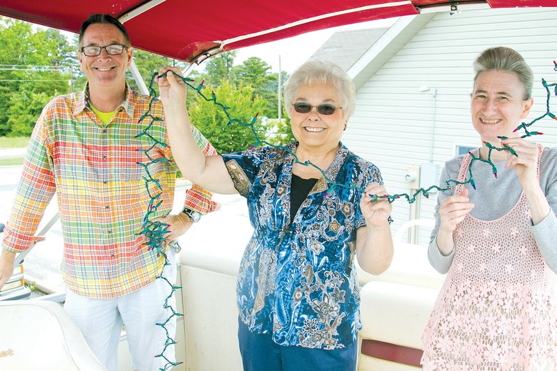 From left, Kevin Thomas, JoAnn Wanat and Vicki Miller of the Greers Ferry Chamber of Commerce string lights on a boat in preparation for the Lighted Boat Parade Contest, coming up June 14.
