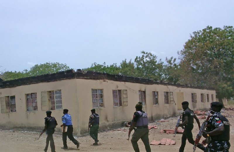 Nigerian security forces walk past a burnt out government secondary school in Chibok, where gunmen abducted more than 200 students in April.