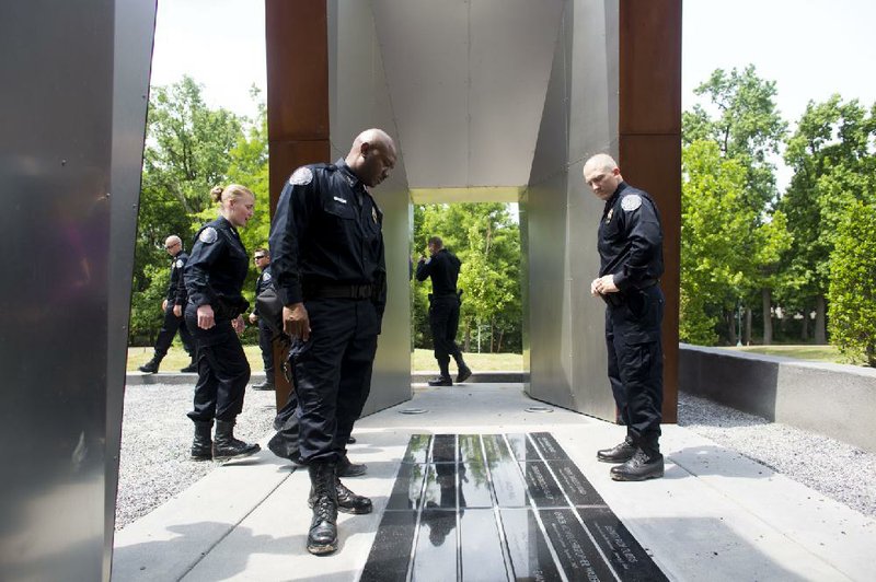 Detective Darell Hayes (front left) and other members of the West Memphis Special Response Team look at a memorial honoring fallen Crittenden County law enforcement officers and a firefighter Thursday at Worthington Park in West Memphis.