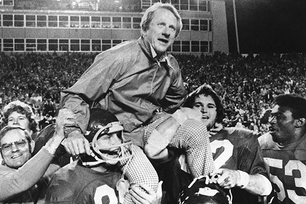 In this Dec. 6, 1975, file photo, Arkansas coach Frank Broyles is carried from the field by players Teddy Barnes, left, and Richard LaFargue (52) following his team's 30-6 NCAA college football game victory over Texas A&M in Little Rock. (AP Photo/Ferd Kaufman, File)