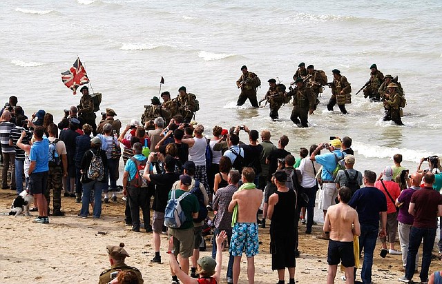 A group of military re-enactors feign a landing of a World War II barge,  on the beach  of Arromanches, France,  Friday, June 6, 2014, as part of D-Day commemorations. World leaders and veterans gathered by the beaches of Normandy on Friday to mark the 70th anniversary of World War Two's D-Day landings. (AP Photo/Claude Paris)
