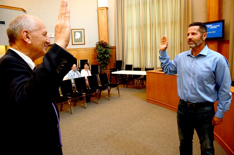 Jeff Della Rosa/Siloam Sunday Brad Burns, right, takes the oath of office before the Board of Directors meeting Tuesday. Burns, the Ward 2 city director, was sworn in by Judge Stephen Thomas.