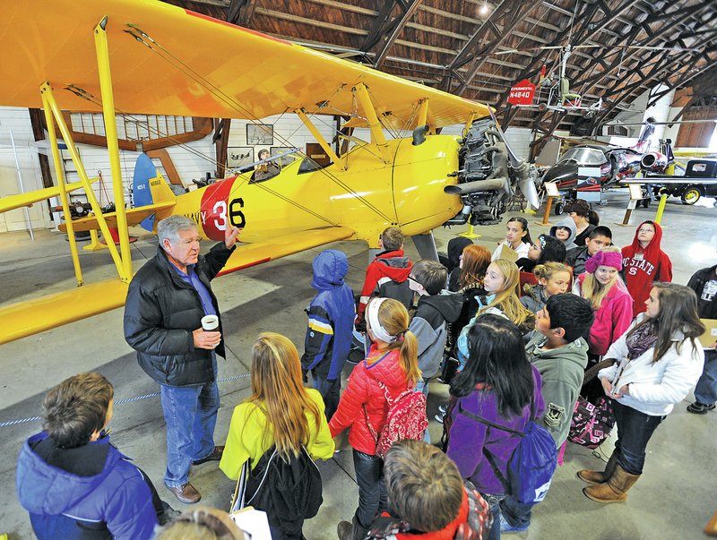 FILE PHOTO ANDY SHUPE Warren Jones, left, executive director of the Arkansas Air and Military Museum, speaks to a group of gifted and talented program students from Kirksey Middle School in Rogers on Feb. 28, 2013, beside a World War II-era Boeing Stearman N2S-2 during a tour of the museum in Fayetteville.