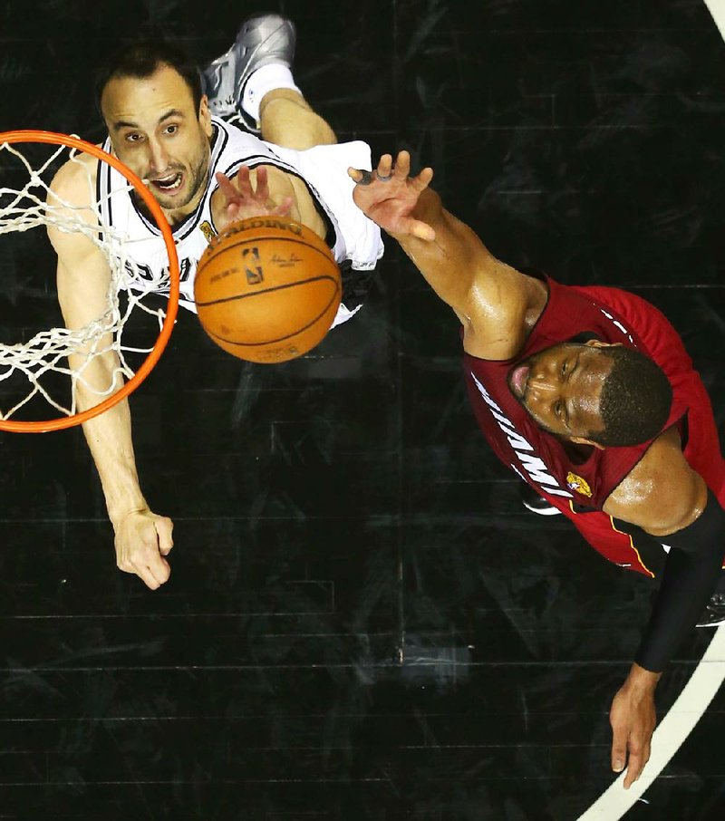 San Antonio Spurs guard Manu Ginobili, left, and Miami Heat guard Dwyane Wade go after the ball during Game 1 of the NBA basketball finals on Thursday, June 5, 2014 in San Antonio. 