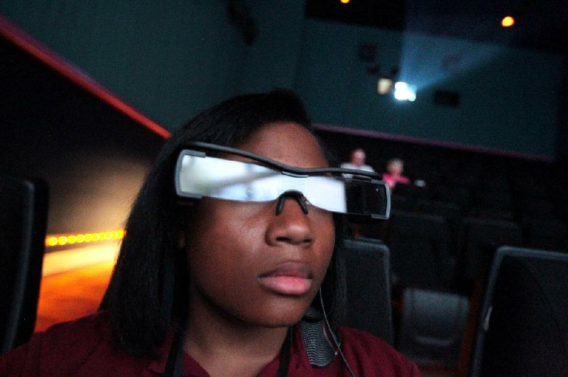 Lauren LeGardye, an usher at Regal Theater in Breckenridge Village, demonstrates Entertainment Access Glasses that allow deaf and hard-of-hearing moviegoers see projected captioning.