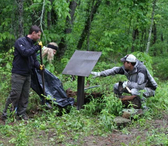 Volunteer trail builders (from left) Larry Kelsor, Kate Kuff and John Sage install a sign beside the new Upper Buffalo Mountain Bike Trail on May 17 in Newton County.