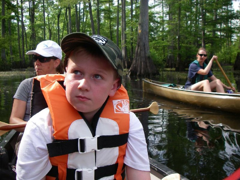 Owen Theus looks for the next blue diamond blaze as he, his mother, Allison Ivey Theus (left), and Kirsten Bartlow, director of the Arkansas Game and Fish Commission’s Arkansas Water Trails program, enjoy a three-hour float May 27 on the new Grassy Lake Water Trail.