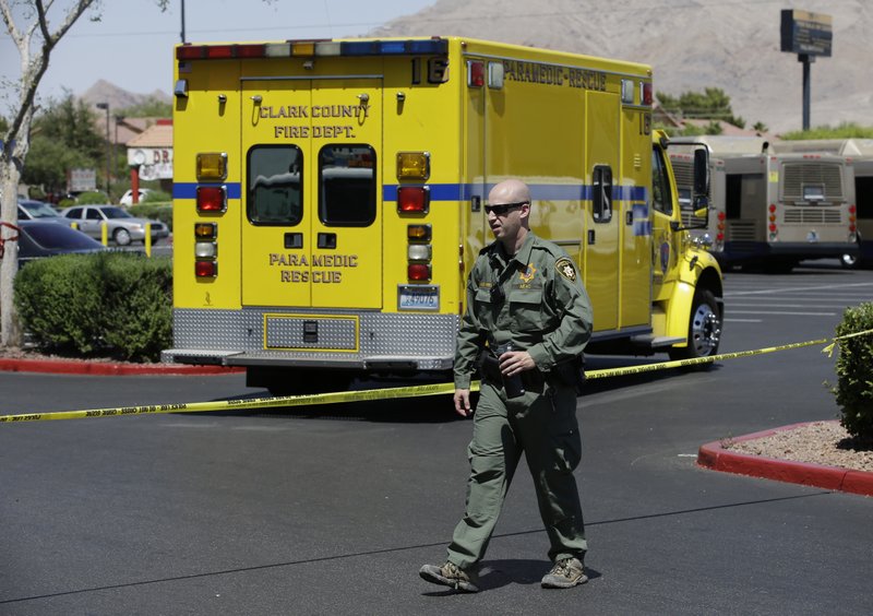 A Las Vegas Metropolitan Police officer walks near the scene of a shooting, Sunday, June 8, 2014 in Las Vegas. Police say two suspects shot two officers at a Las Vegas pizza parlor before fatally shooting a person and turning the guns on themselves at a nearby Walmart.
