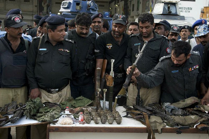 Pakistani police officers display weapons and ammunition confiscated from attackers at the Jinnah International Airport on Monday in Karachi, Pakistan.