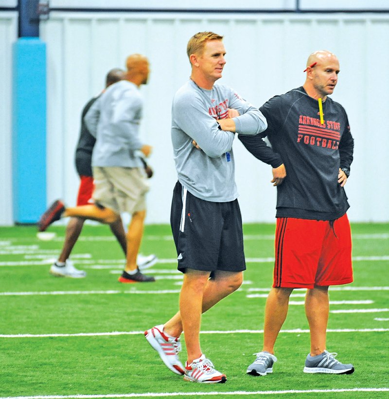 STAFF PHOTO ANDY SHUPE Blake Anderson, head coach at Arkansas State, center, speaks Sunday with assistant coach Brian Early, a former Fayetteville High School assistant coach, during a football camp organized by the university at Springdale Har-Ber.