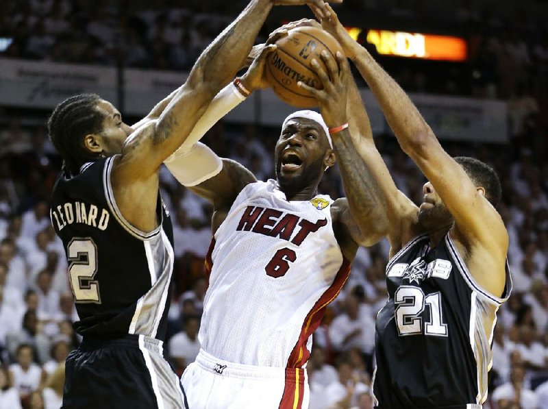 San Antonio’s Kawhi Leonard (2) and Tim Duncan (21) try to keep Miami’s LeBron James from getting off a shot Tuesday in the first half of the Spurs’ 111-92 victory in Miami. Leonard had a game-high 29 points, and James had 22 for the Heat.