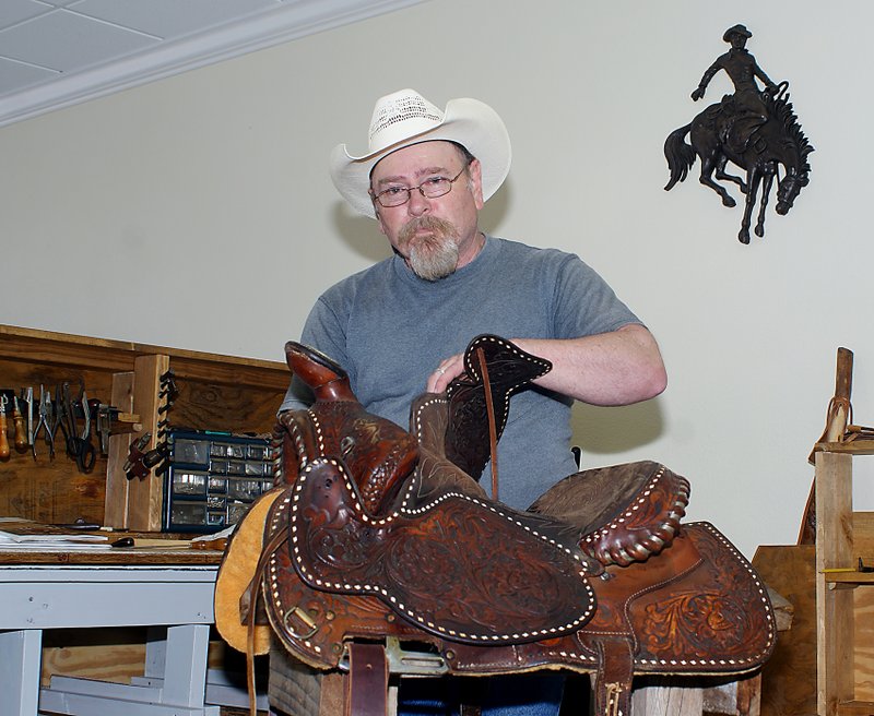 Photo by Randy Moll John Stamps works on a saddle at his new Main Street shop in Gentry. The new business, which makes and sells custom boots, saddles and tack, opened in early May.