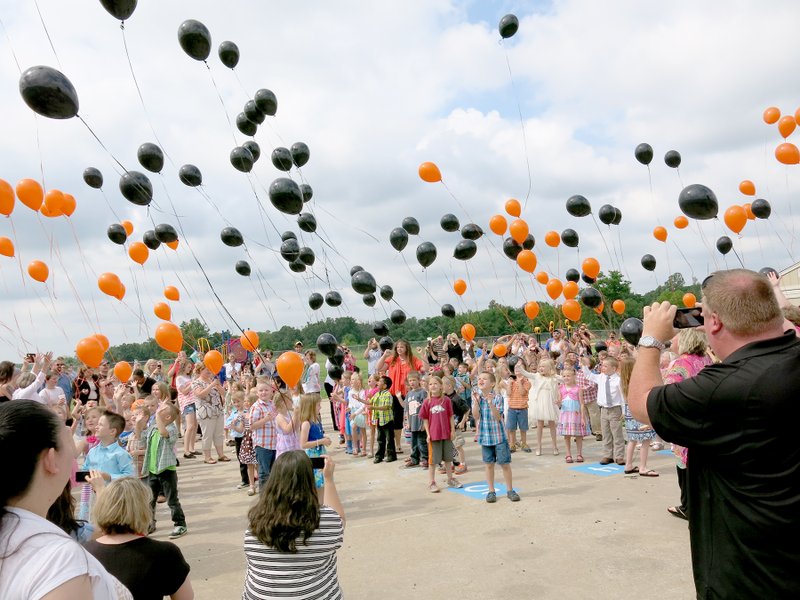 Photo by Susan Holland Kindergarten students, their teachers and many of their parents and family members gathered on the Glenn Duffy Elementary playground following their graduation ceremonies last Tuesday morning and celebrated with a balloon release. Dozens of black and orange balloons were released and a brisk breeze soon carried them up and away. The balloons were provided by The Balloon Closet of Siloam Springs and were 100 percent biodegradable.