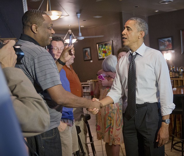 President Barack Obama greets patrons after having lunch during an unannounced visit to FireFlies restaurant in the Del Ray neighborhood of Alexandria, Va. ,Tuesday, June 10, 2014. President Barack Obama and Education Secretary Arne Duncan, went on a lunch outing to an Alexandria, Virginia, neighborhood known for its good restaurants. The White House said Obama went to FireFlies Restaurant on Tuesday because the owner wrote him earlier this year and asked him to come try the best burger around.
