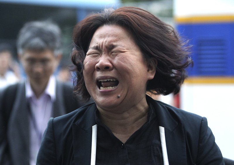A family member of passengers aboard the sunken ferry Sewol cries after a pretrial hearing of crew members of the ferry at Gwangju District Court in Gwangju, South Korea, Tuesday, June 10, 2014. Hostile spectators cursing, shouting and weeping behind them, 15 crew members from the sunken South Korean ferry appeared in court Tuesday to enter pleas on charges of negligence and failing to save more than 300 dead or missing passengers. 