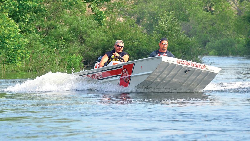 Steve Heide, left, and Mike Prichar of the Caddo Valley Fire Department speed around the rolling current on the Caddo River to learn how to maneuver in a strong current.