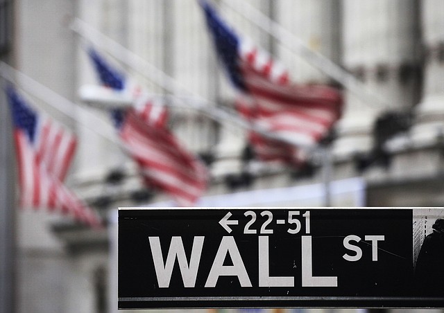 This file photo made April 22, 2010 shows a Wall Street sign in front of the New York Stock Exchange. U.S. stock futures slipped Wednesday, June 11, 2014, after the World Bank downgraded its forecast for the global economy this year, citing a bitter American winter and the political crisis in Ukraine.