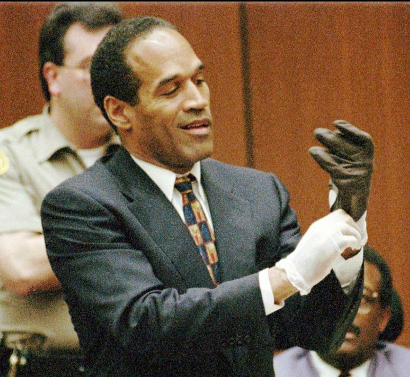 Murder defendant O.J. Simpson tries on one of the leather gloves that prosecutors said he wore the night of the murders of his ex-wife Nicole Brown Simpson and Ron Goldman. The 1995 trial is the subject of a new special on cable’s ID network.