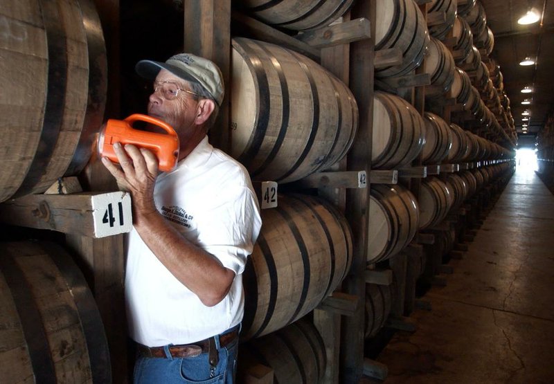 An employee of the George Dickel Distillery near Tullahoma, Tenn., checks for leaks from barrels of whiskey aging in a rack house in this 2003 file photo. The owners of Dickel and Jack Daniel’s are in a battle over who has the right to label their drink as following authentic Tennessee whiskey.