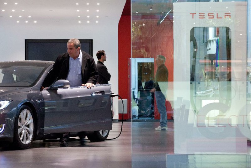 A visitor steps into a Tesla Motors Inc. Model S at the company’s store in the Short Hills Mall in Short Hills, N.J. earlier this year. Tesla CEO Elon Musk said Thursday that the company is making all its patents public.