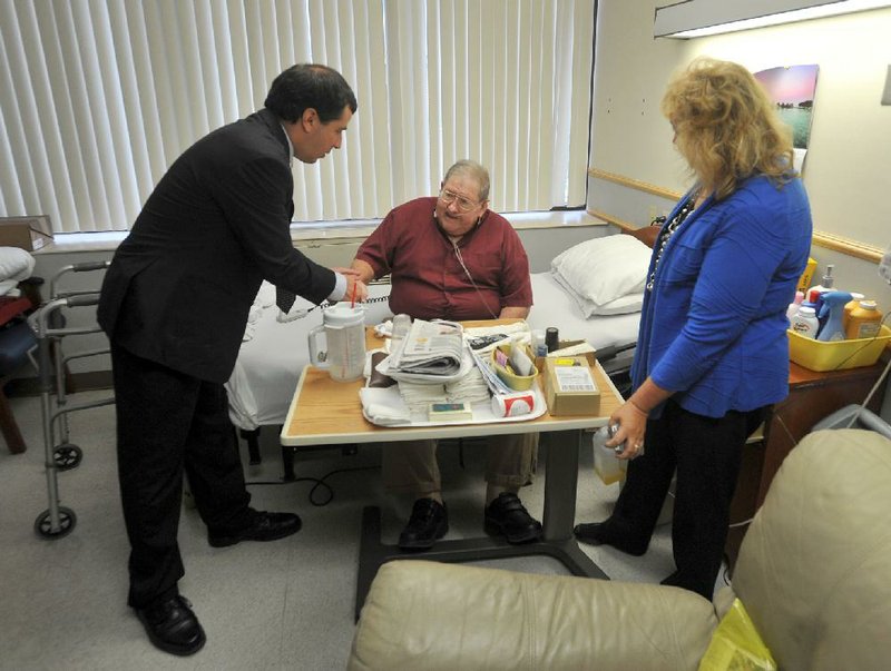 Rep. David Meeks, R-Conway, and Rep. Sue Scott, R-Rogers, visit Thursday with World War II and Korean War veteran Tom Bass during a tour of the Fayetteville Veterans Home.